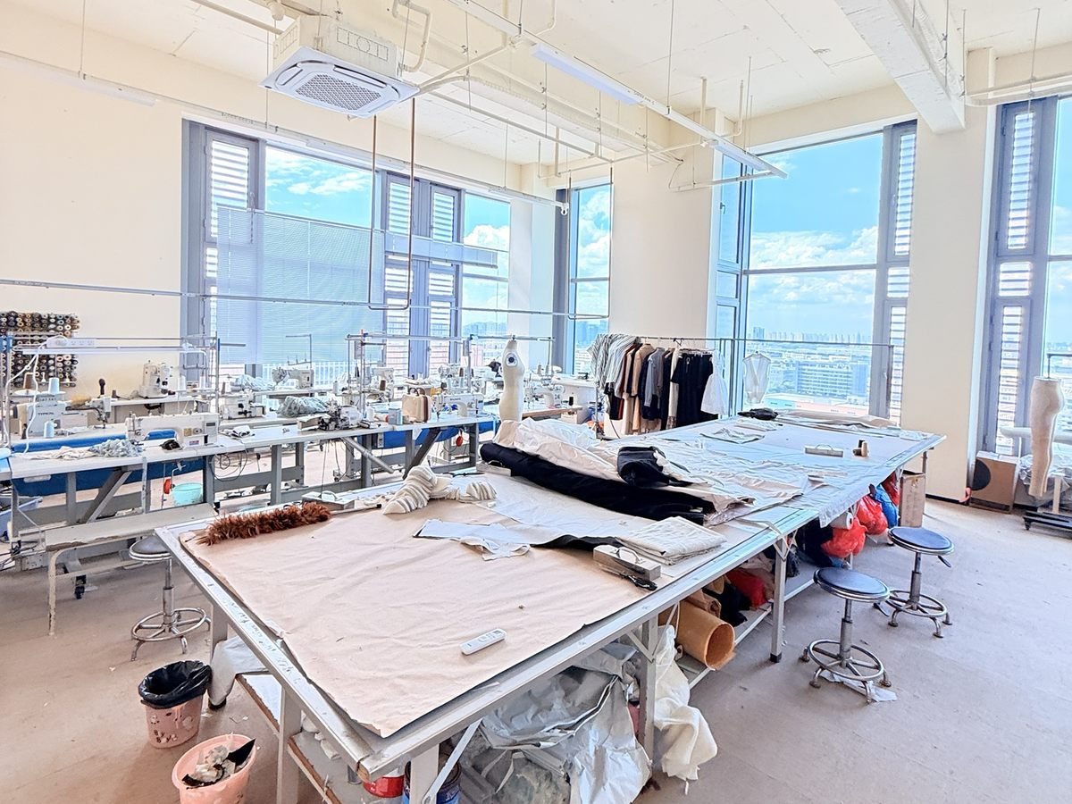 服装设计打样板房,展示裁剪台、缝纫设备和样衣
